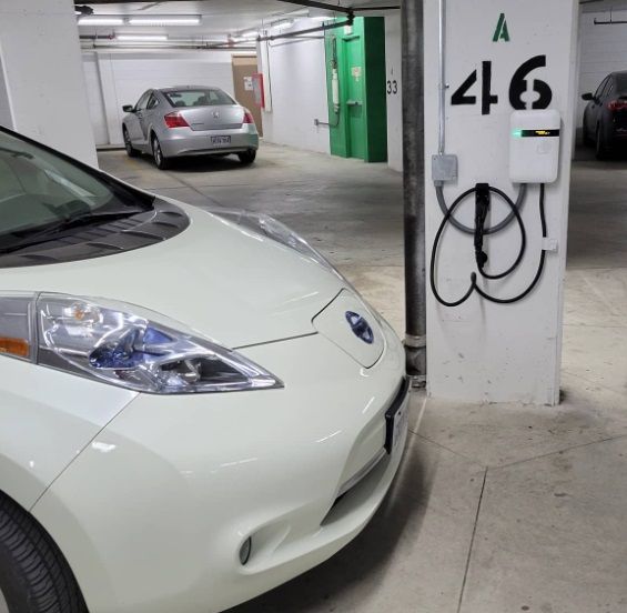 A white car is parked next to a wall with the number 46 on it