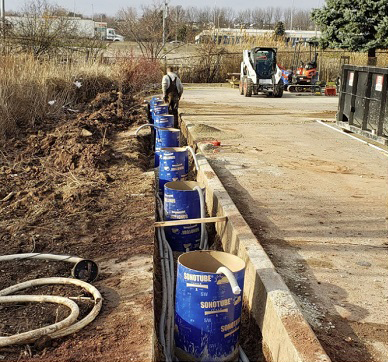 A row of blue barrels are lined up on the side of a road