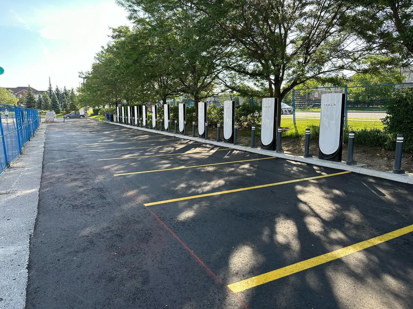 A parking lot with a row of charging stations on the side of it.