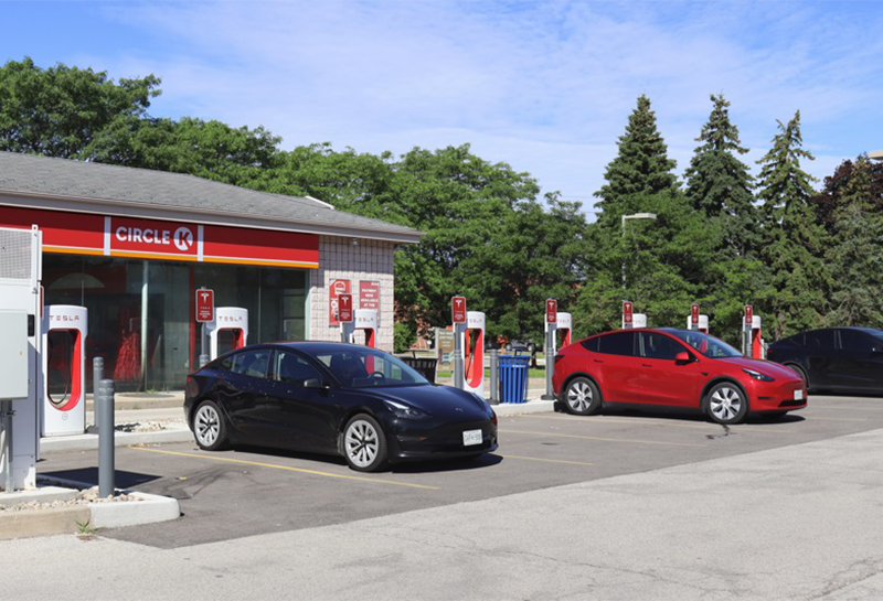 Three electric cars are parked in front of a charging station.