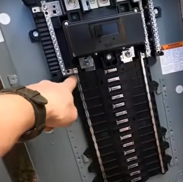 A person wearing a watch is working on a electrical panel.