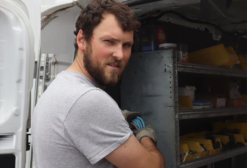 A man with a beard is standing in front of a van.