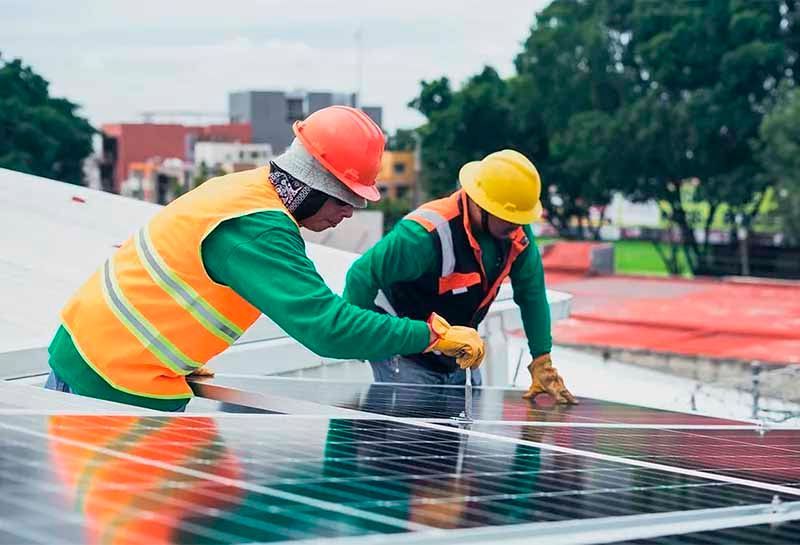 Two men are installing solar panels on the roof of a building.