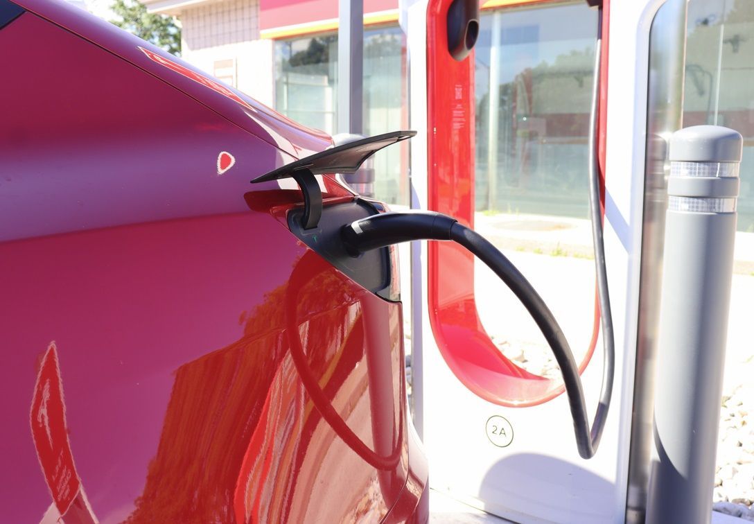 A red electric car is being charged at a charging station.