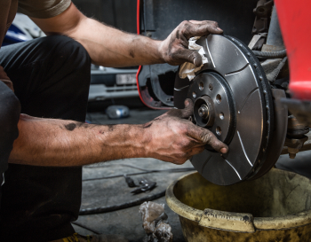 Technician installing new set of brakes on vehicle | Rockford Auto Inc