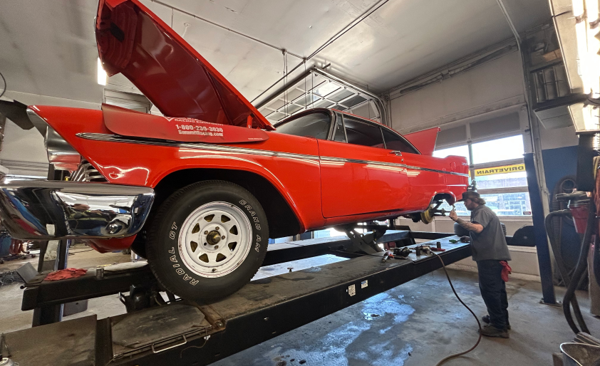 Man in garage working on red car with hood open | Rockford Auto Inc