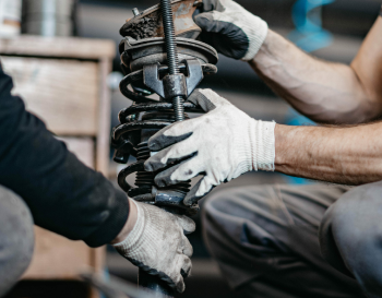 Two mechanics working with suspension piece | Rockford Auto Inc