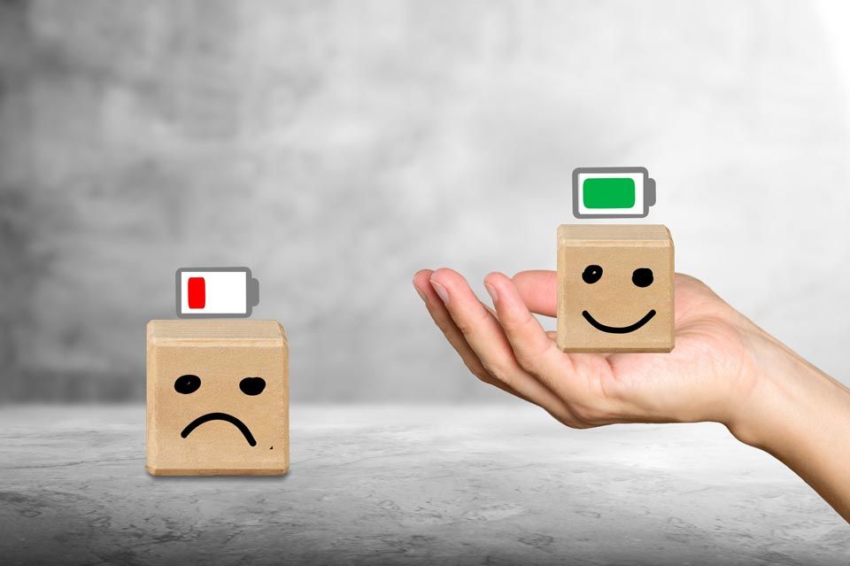 Eine Hand hält zwei Holzklötze mit Smileys darauf.
