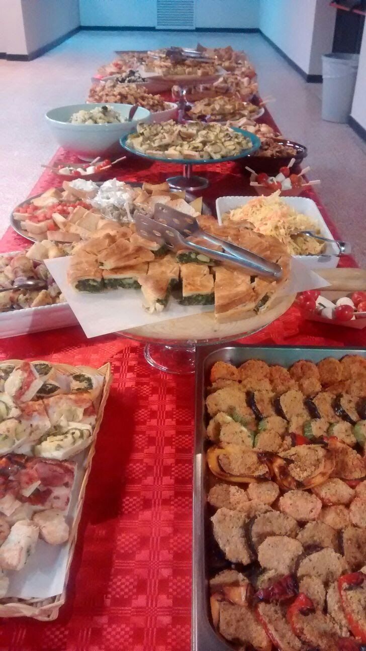 Un buffet con un assortimento di antipasti e dessert su tovaglie rosse in una stanza luminosa.