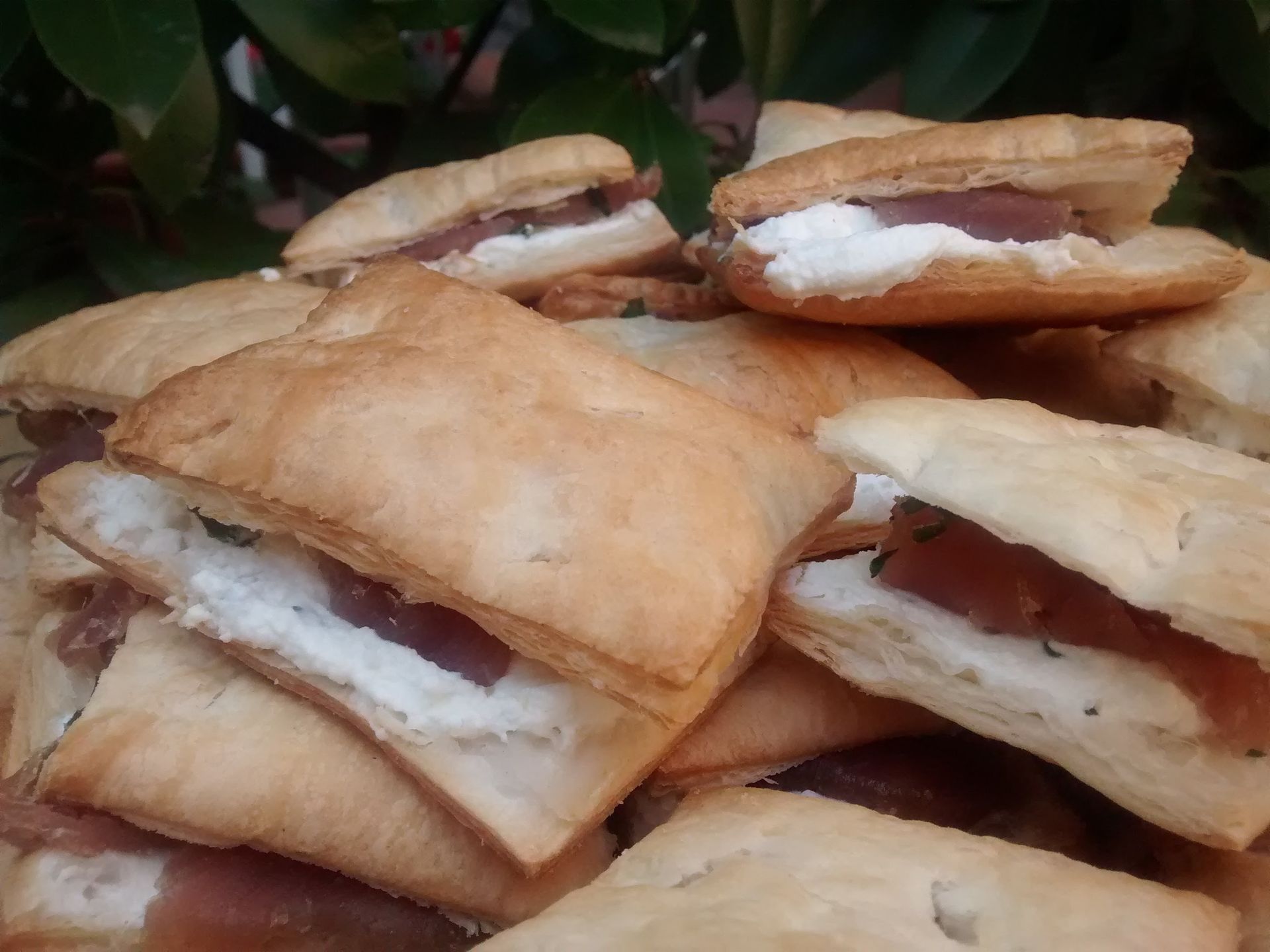Pila di pasticcini ripieni dorati con ripieno bianco, ammucchiati su un vassoio all'aperto