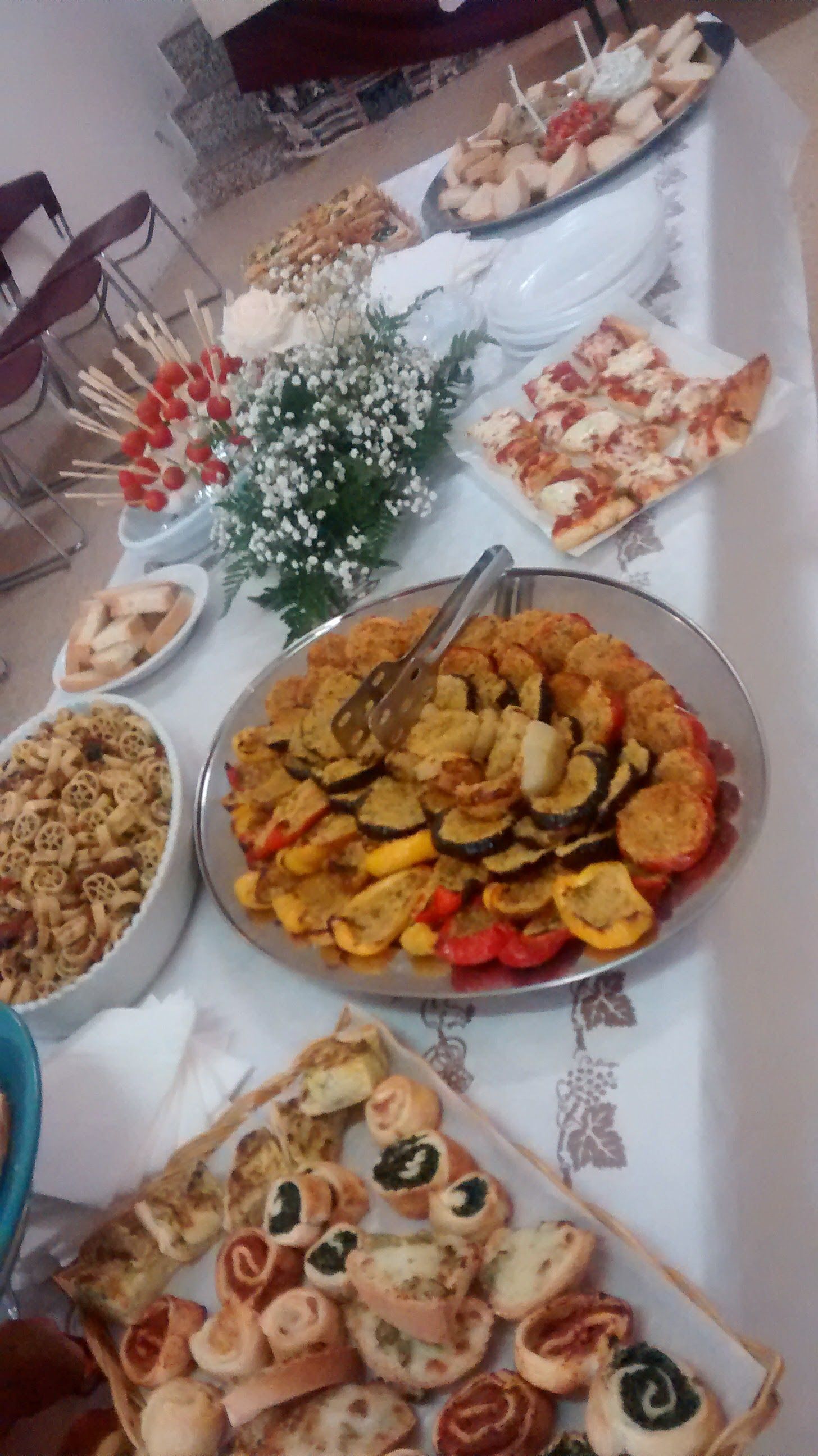 Tavolo da banchetto con piatti assortiti, pasticcini e fiori in una luminosa sala da pranzo.
