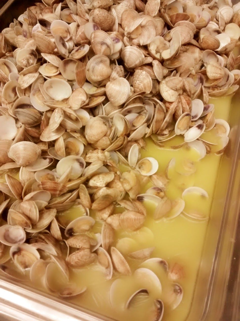 Un vassoio di gusci di pistacchio accanto a una pozza di liquido giallo.
