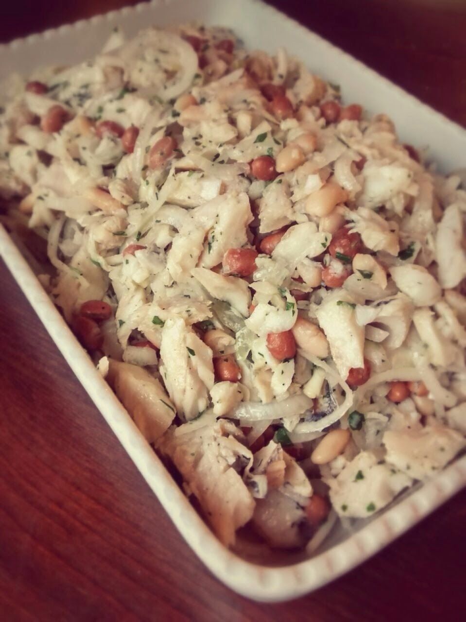 Insalata di pasta cremosa con erbe aromatiche e verdure a dadini in un piatto rettangolare bianco.