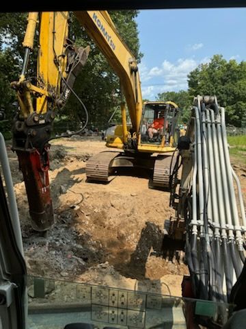 A man is driving a yellow excavator on a construction site.