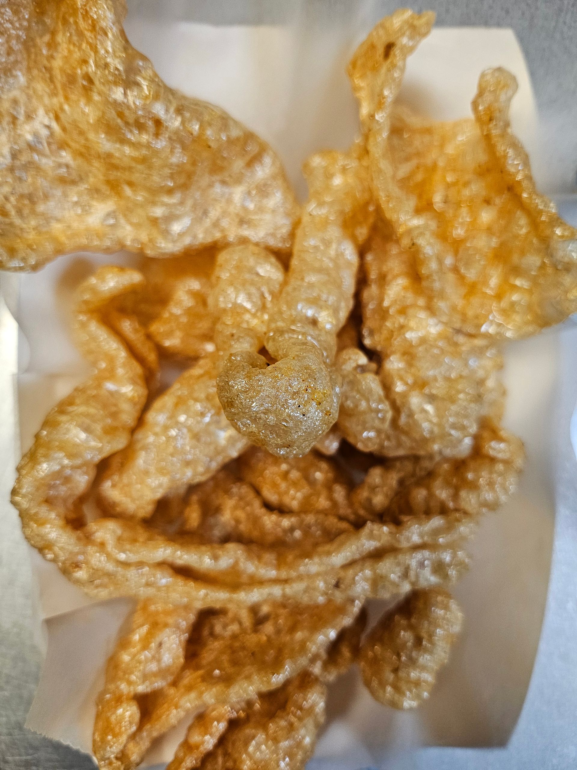 A close up of a tray of pork rinds on a table.