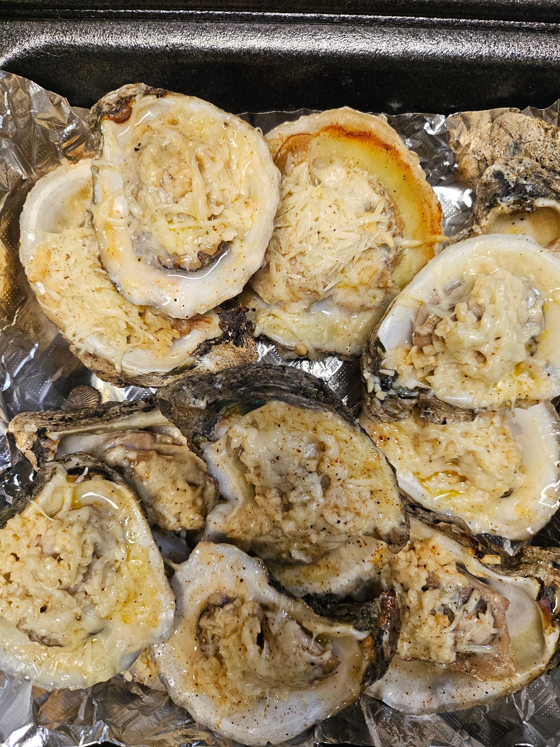 A bunch of oysters are sitting on top of a piece of tin foil.
