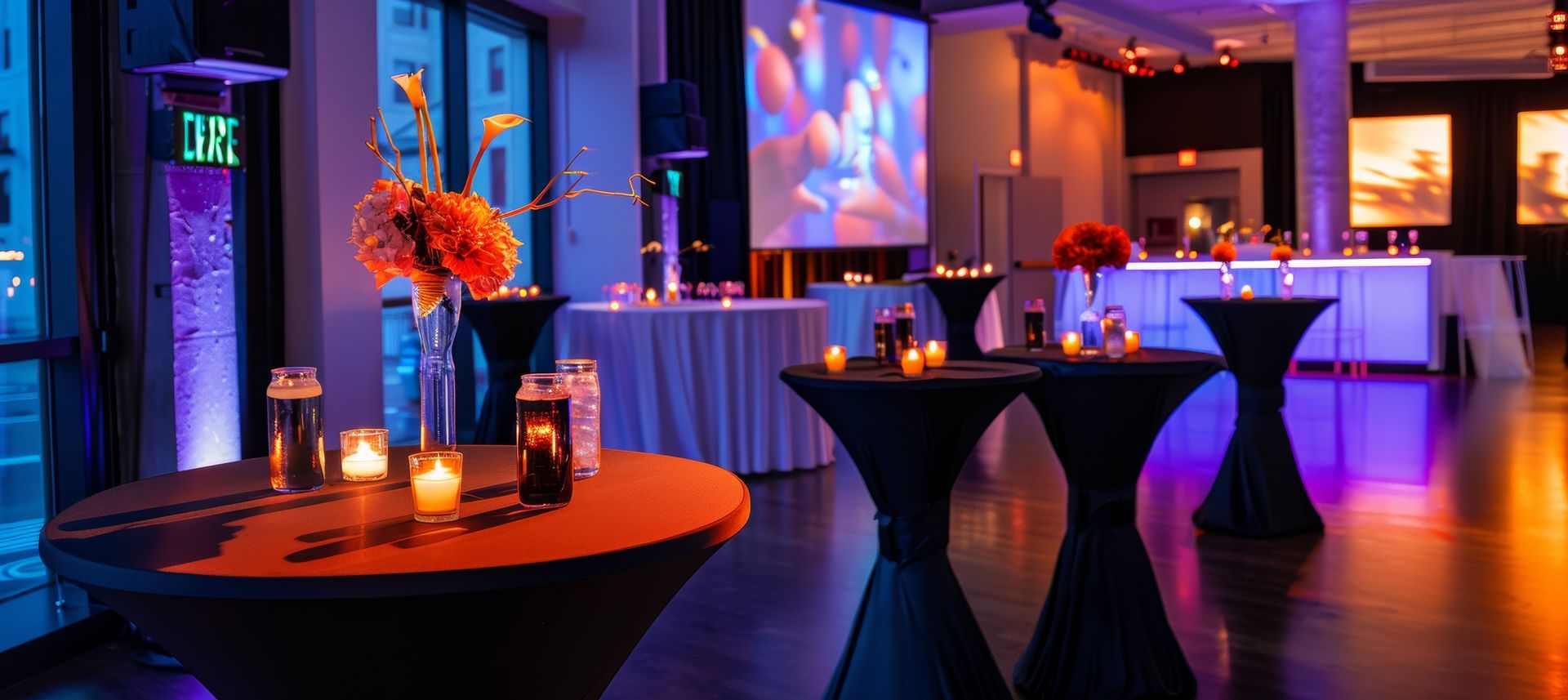 A room filled with tables and candles and a projector screen.