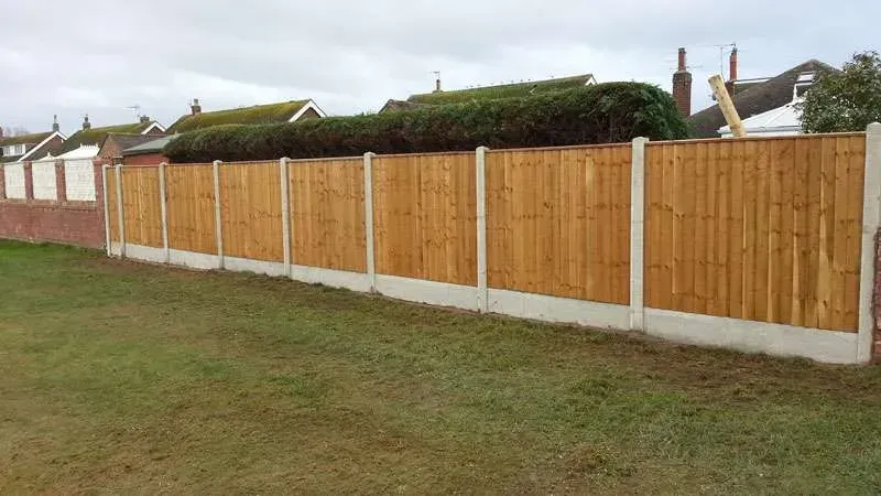 A wooden fence is sitting in the middle of a lush green field.
