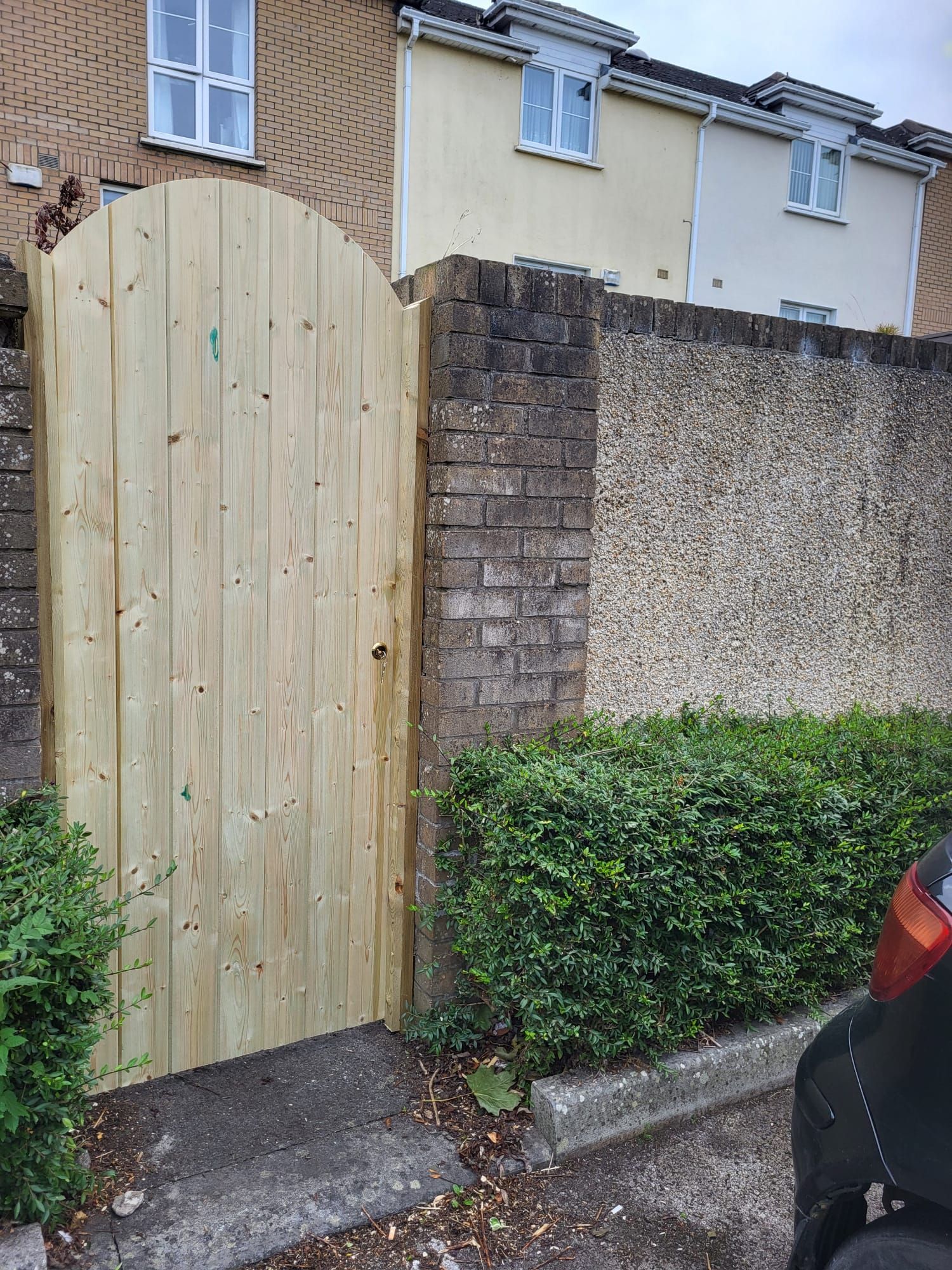 A wooden gate is sitting next to a brick wall.