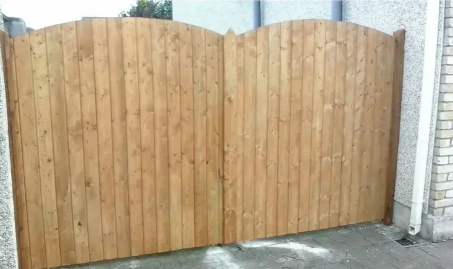 A wooden fence is sitting next to a brick wall.