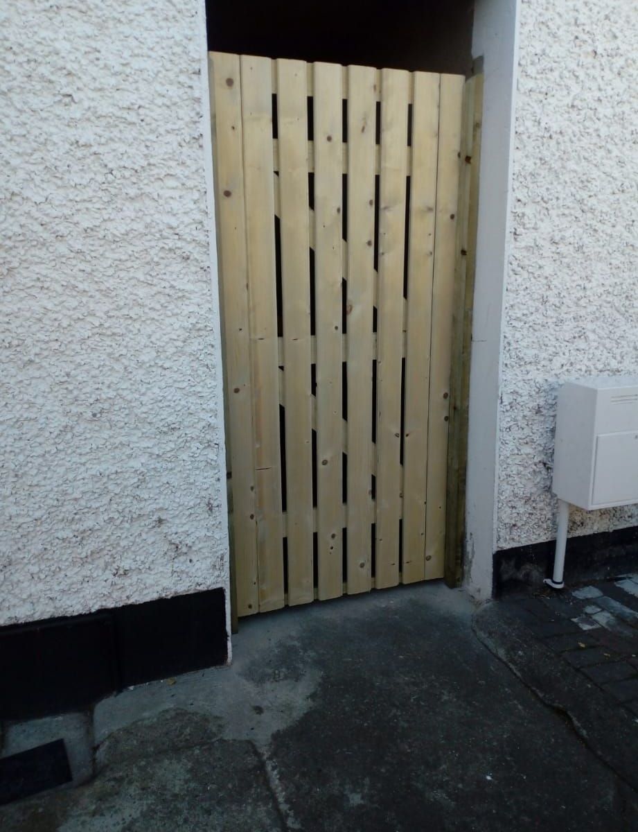 A white wall with a wooden gate in front of it