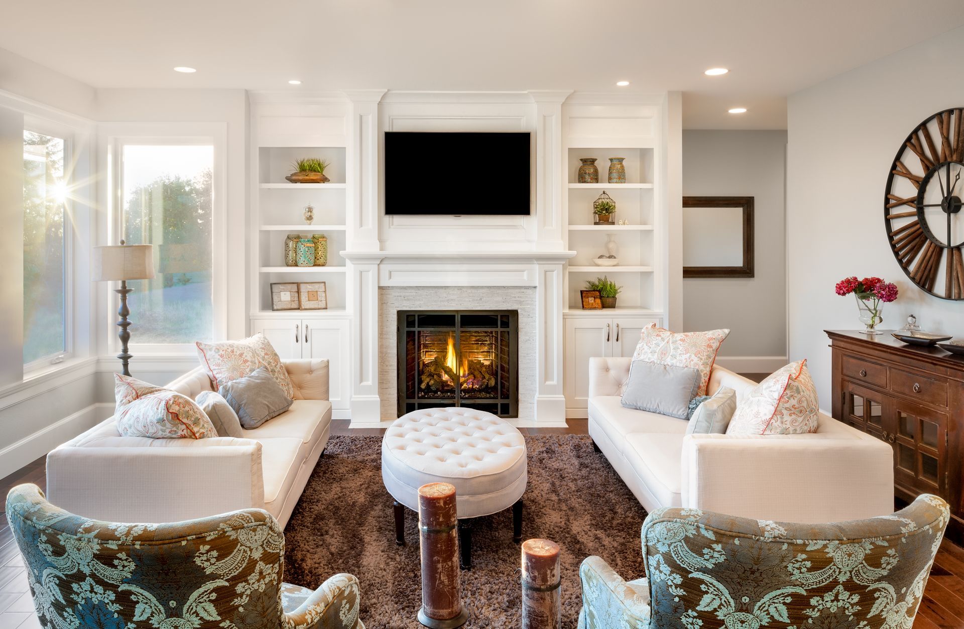 Living room with fireplace, white couches, built-in shelves, and a large wall clock.