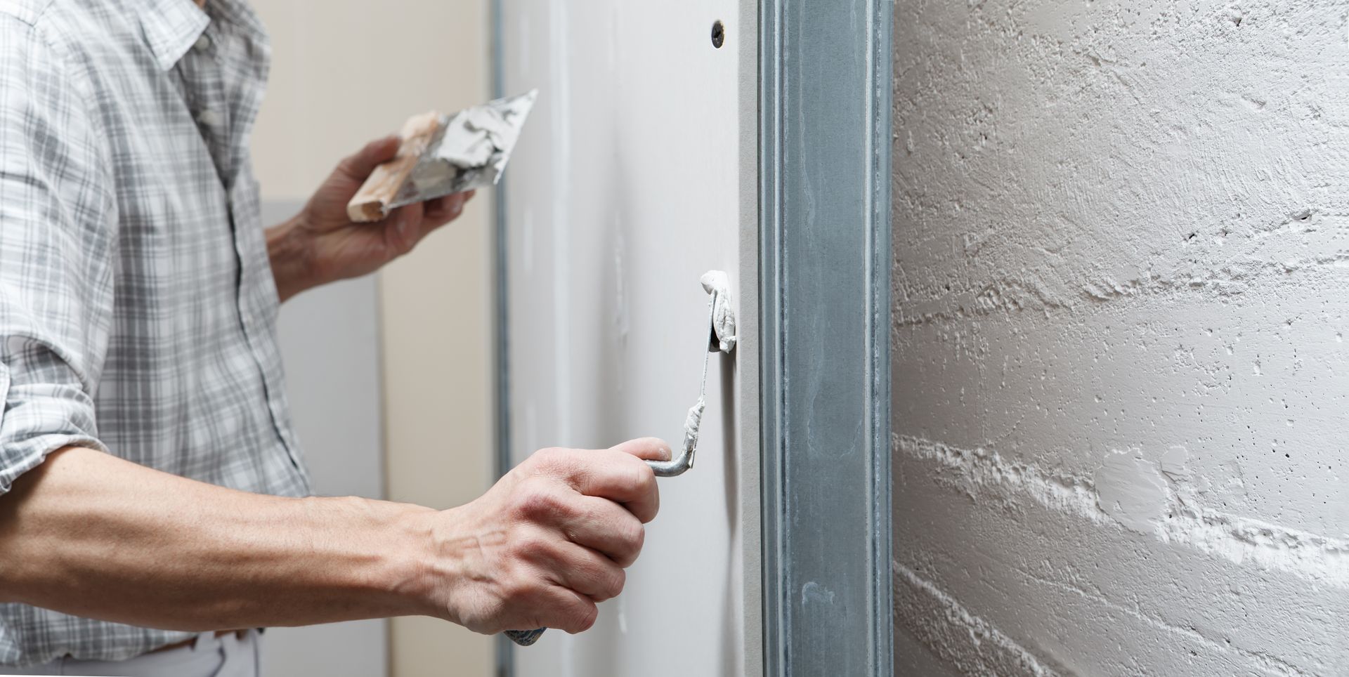 Person applying plaster with a trowel to a wall.