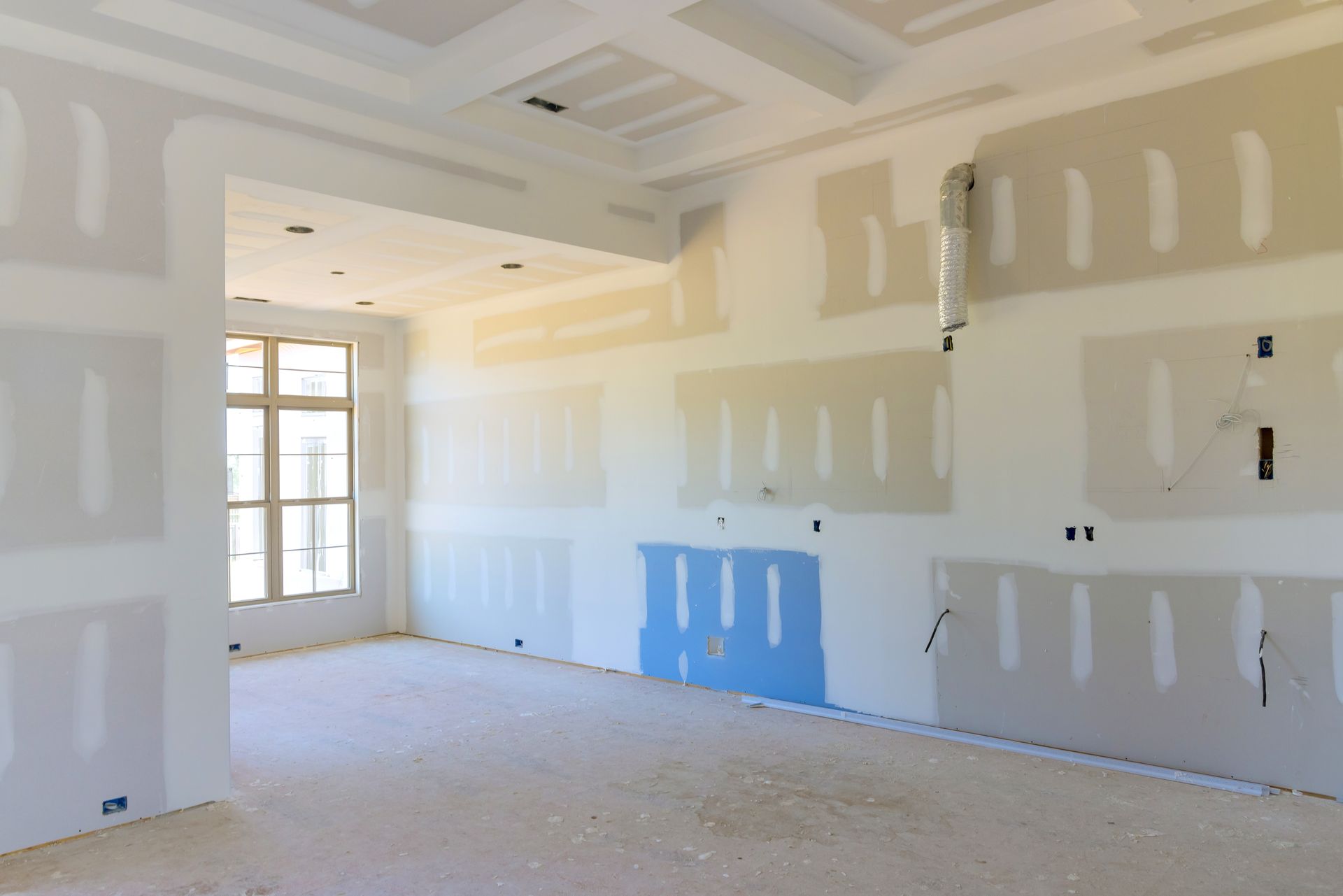 Interior room under construction with drywall and exposed studs.