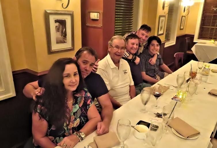 Group of people seated at a restaurant table, smiling during a dinner gathering.