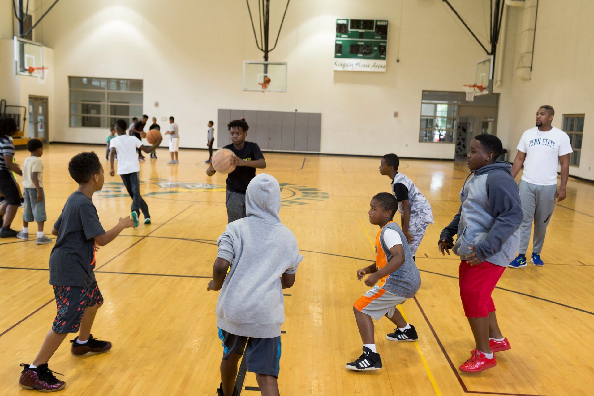 A group of young boys are playing basketball in a gym.
