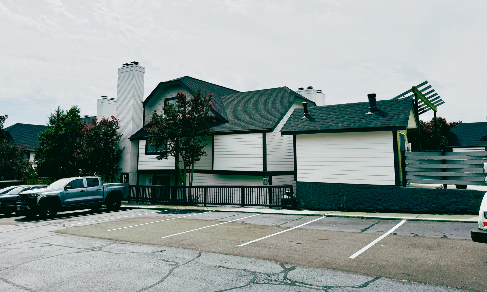 Damaged house with collapsed roof and boarded windows in a parking lot after a storm.