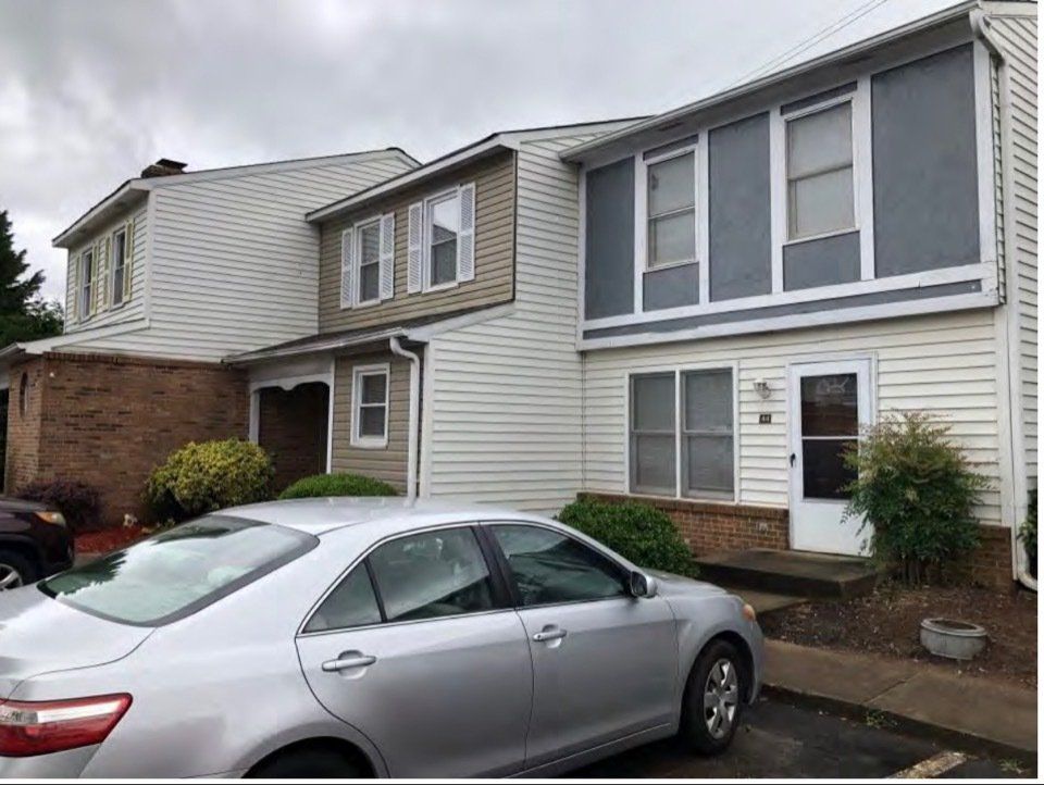 Row of suburban townhouses with a silver car parked in front on a cloudy day