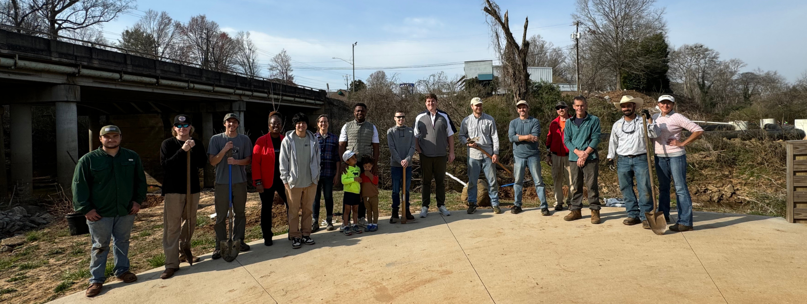 Group of people standing in front of a weathered structure on a sunny day.