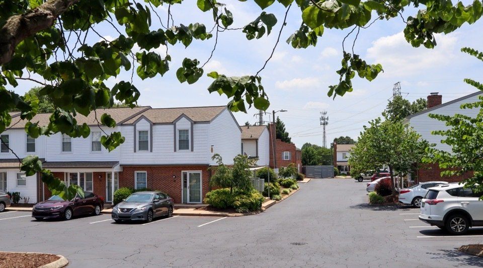 Suburban townhouse courtyard with parked cars and trees on a sunny day