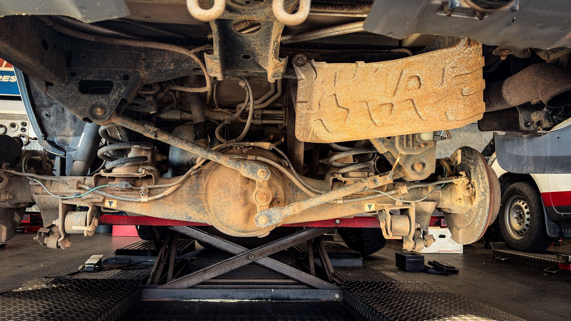 Mechanic's underside view of a car's rear axle, differential, and suspension on a lift at AutoWits in Scottsdale