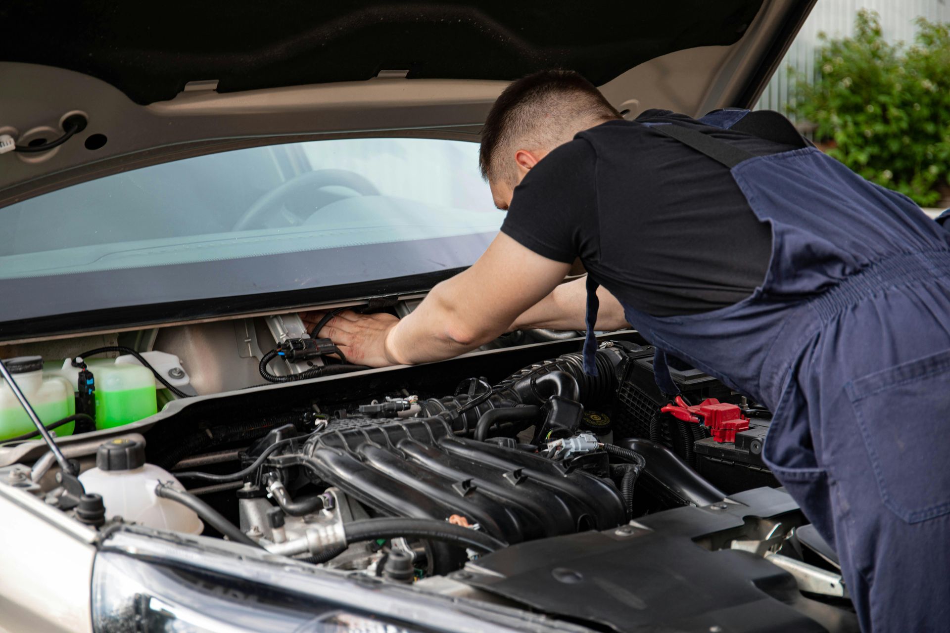 Mechanic inspecting car engine during spring maintenance at AutoWits in Scottsdale AZ