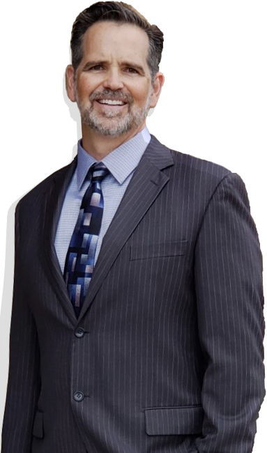 Studio portrait of a smiling man in a dark pinstripe suit and blue tie, standing against a white background