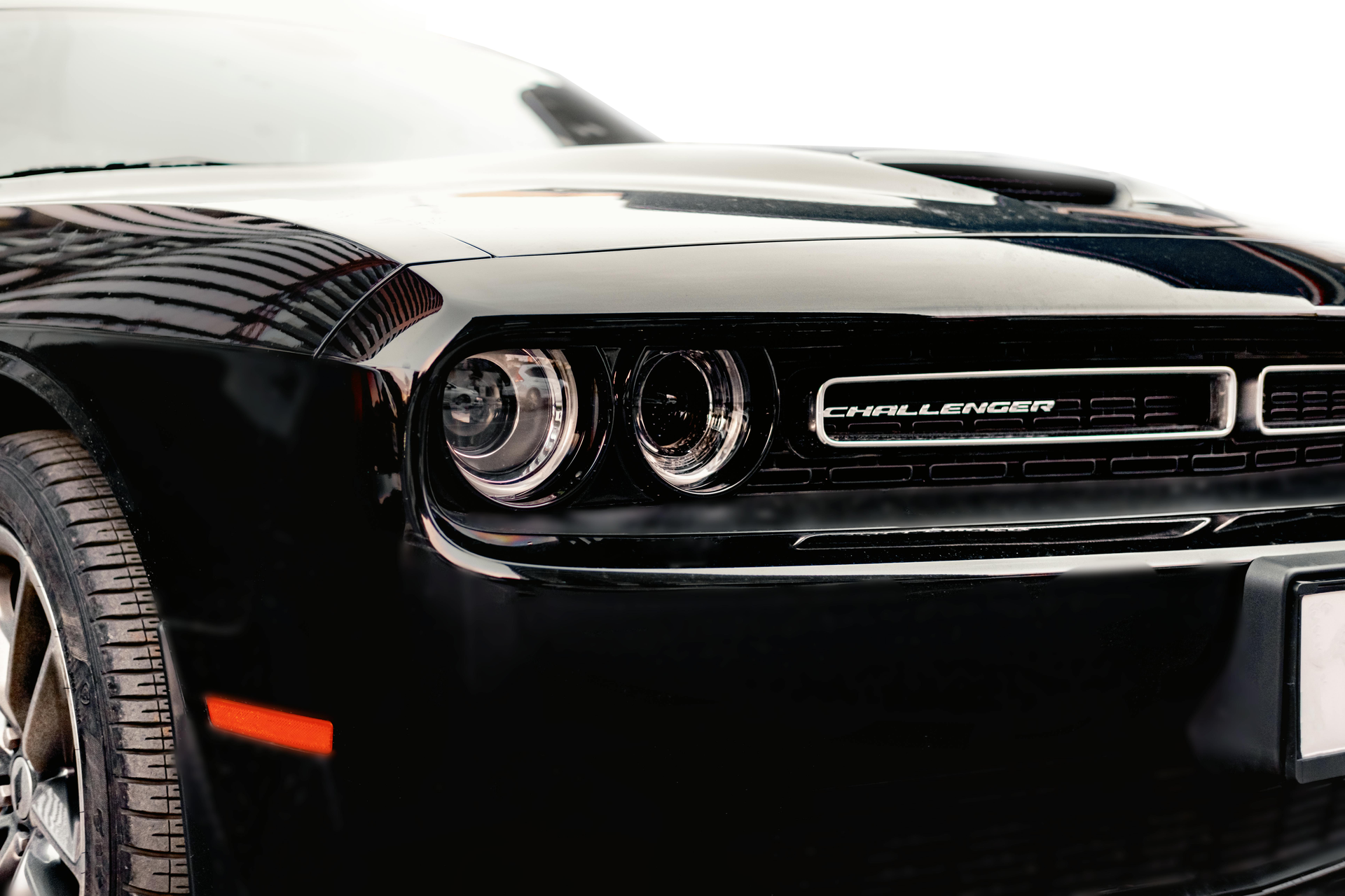 Black Dodge Challenger front view with headlights and grille visible on a white background