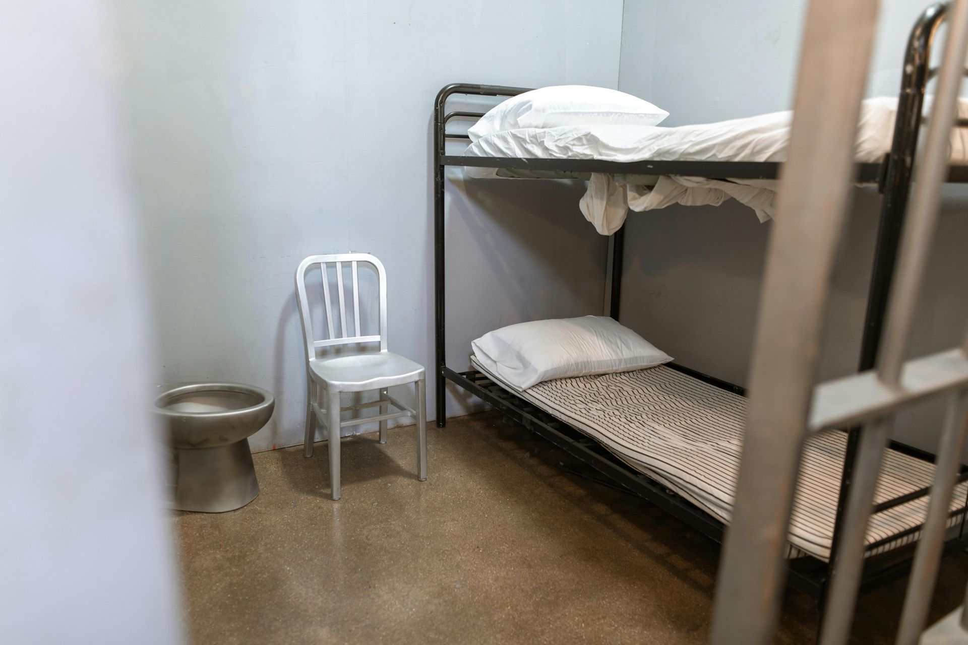 Prison cell: bunk beds, toilet, metal chair.