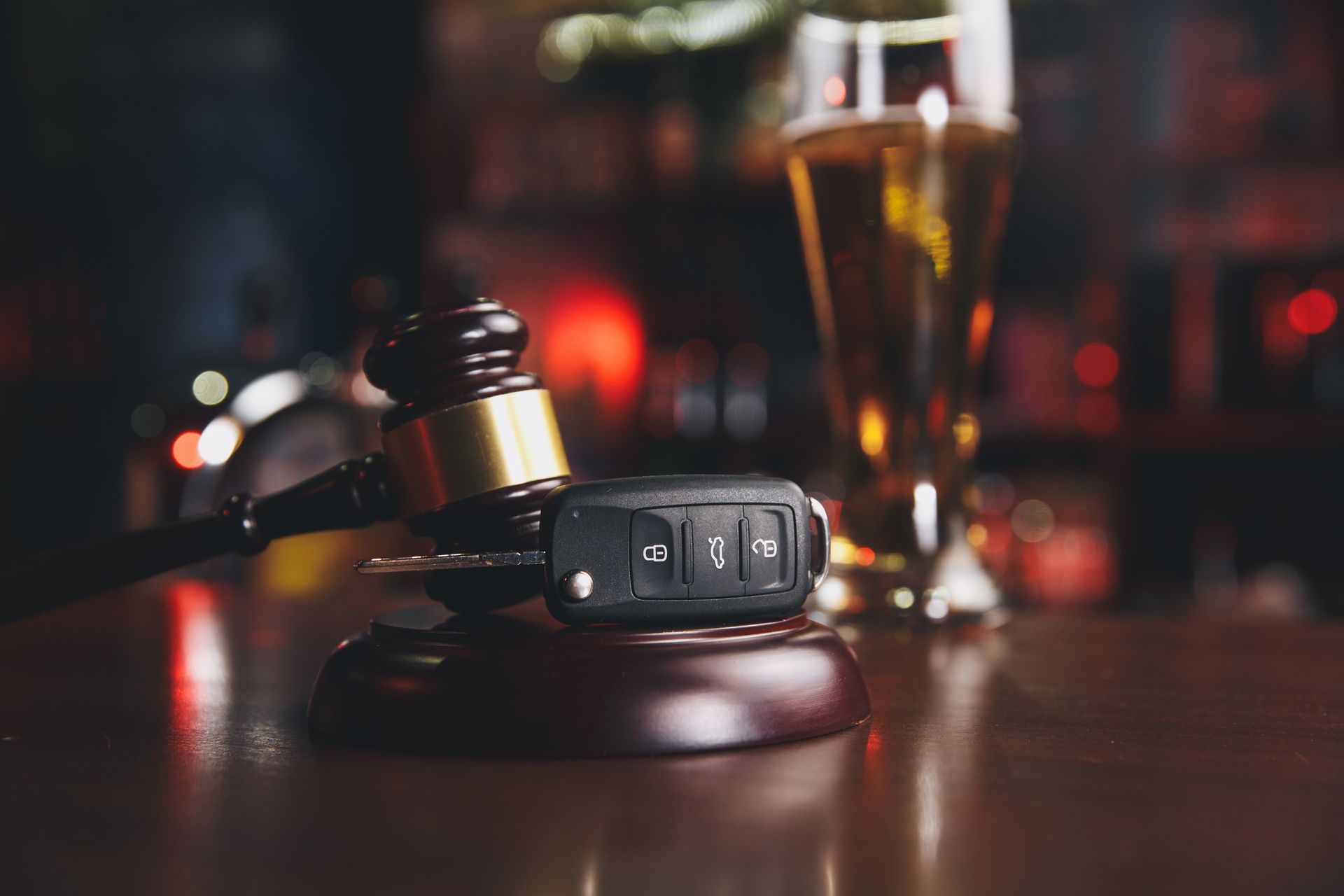 Car keys on a judge’s gavel with a beer glass in the background. Car keys on a judge’s gavel with a beer glass in the background.