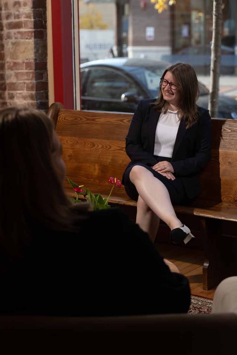 A woman is sitting on a bench talking to another woman.
