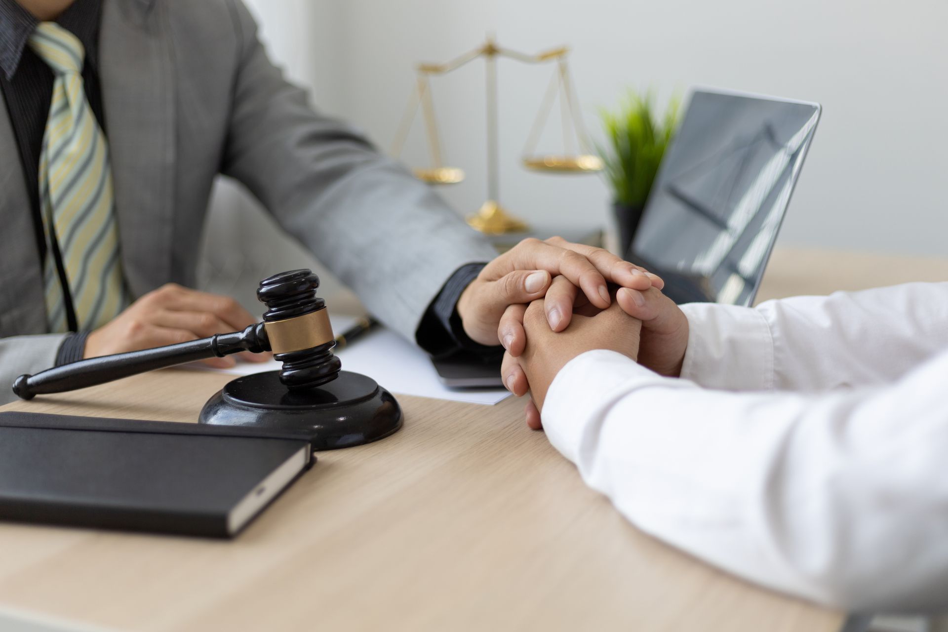 An OWI lawyer consoling his client by putting his hand over his. Desk with gavel, planner, and laptop. An OWI lawyer consoling his client by putting his hand over his. Desk with gavel, planner, and laptop.
