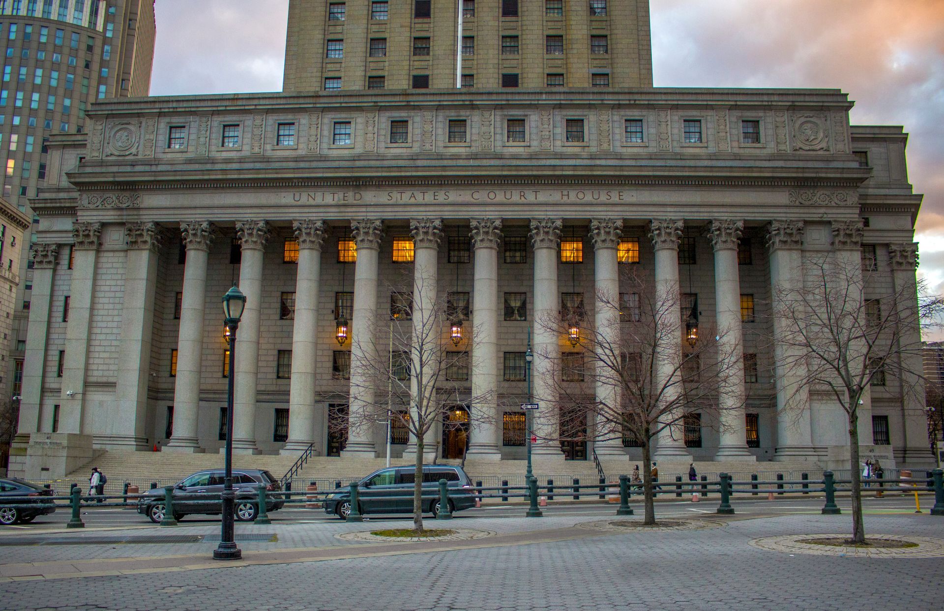 A Large Building with Columns and Cars Parked in Front of It. A Large Building with Columns and Cars Parked in Front of It.
