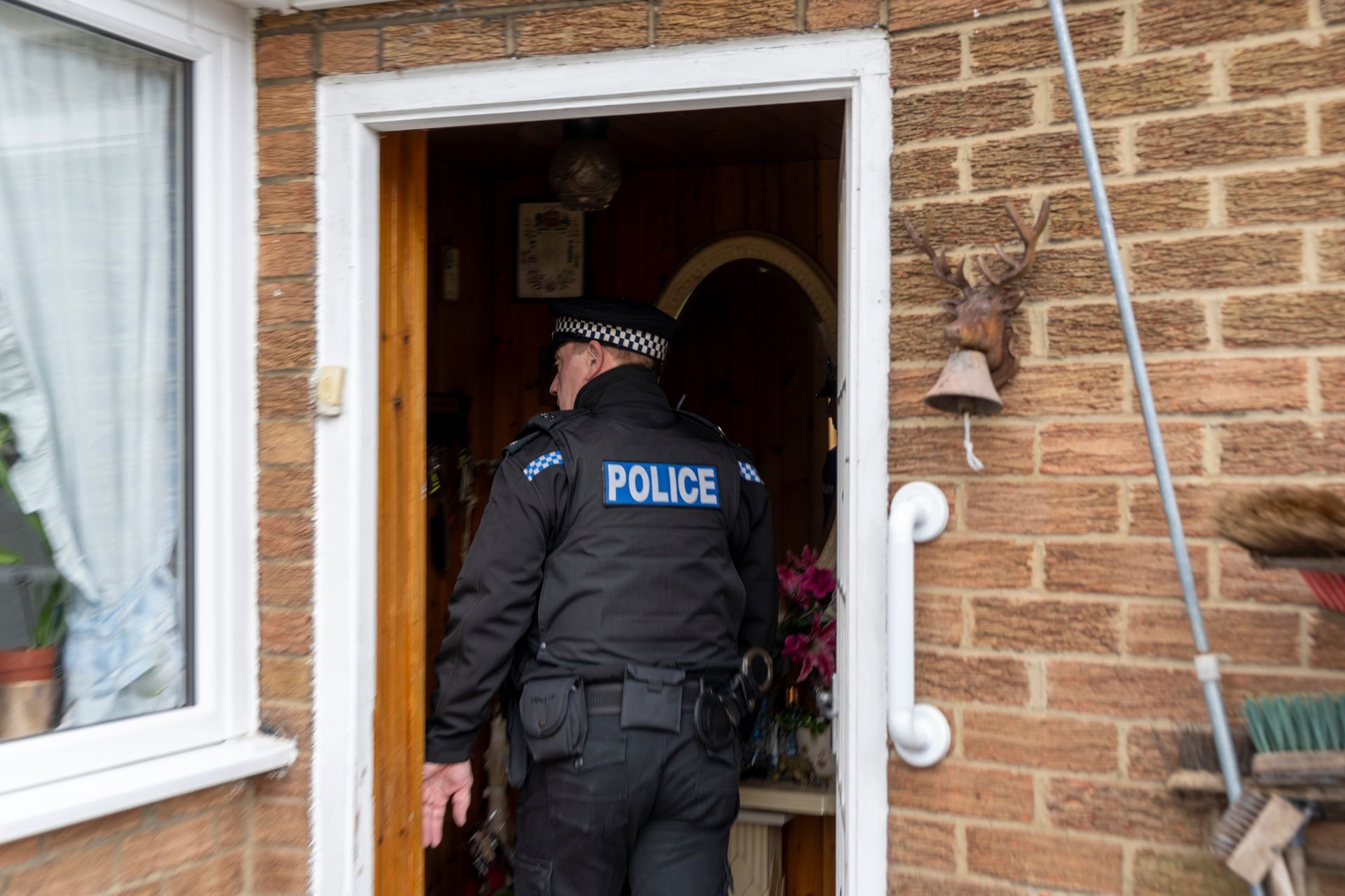A police officer is standing in the doorway of a house. A police officer is standing in the doorway of a house.