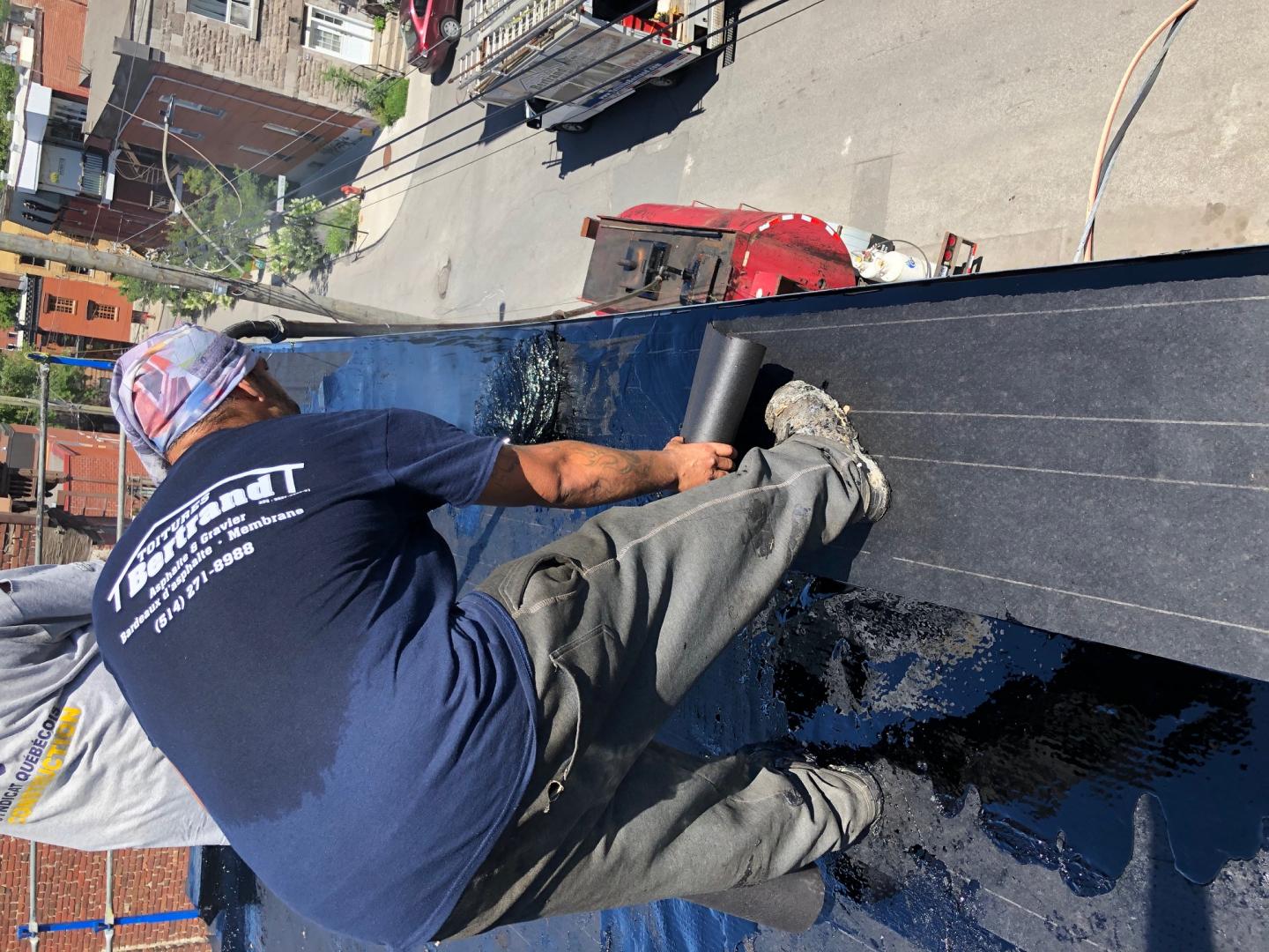 A man in a blue shirt is working on a roof.