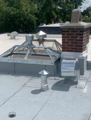 A roof with a brick chimney and a skylight