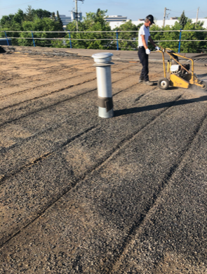A man is working on a roof with a machine.