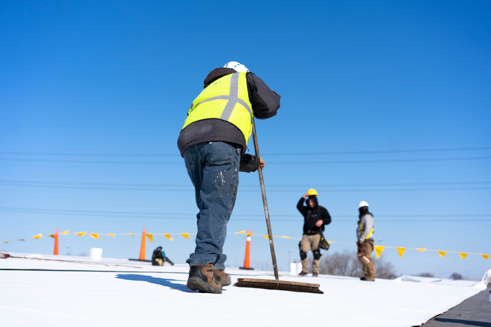 A man is sweeping the snow on a roof with a broom.