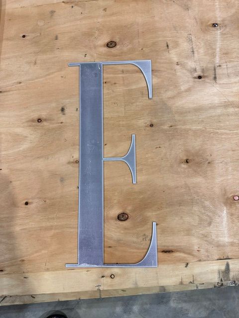 Large blue letter E mounted on a wooden wall.