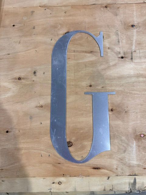 Large blue letter G mounted on a wooden plank wall